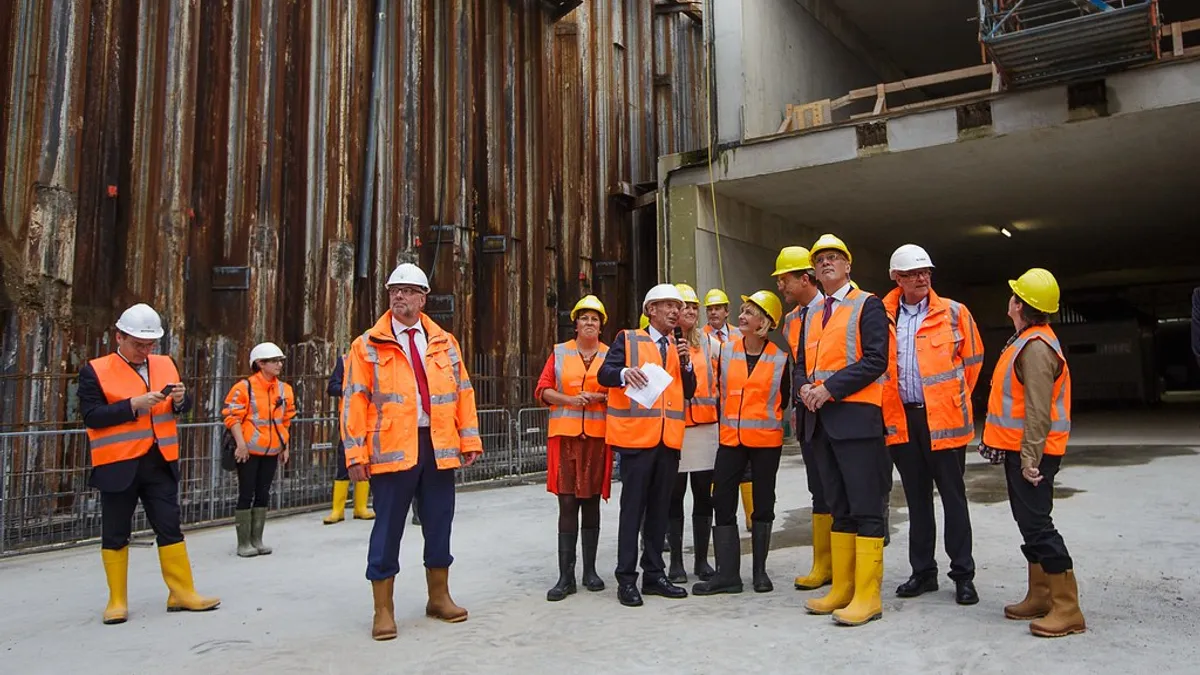 Bedrijfsbusverzekering voor de bouw en aannemers Bouwvakkers in oranje veiligheidskleding op een bouwplaats